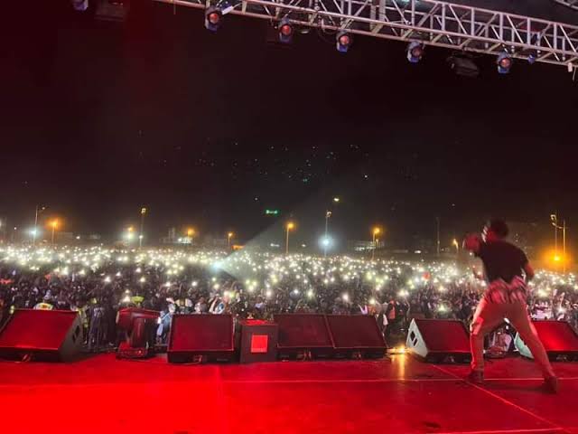 Concert en plein air de nuit, foule éclairée par les téléphones